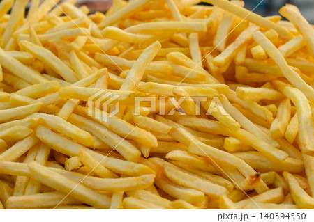 Golden crispy french fries fast food indulgence unhealthy eating snack food deep fried potato sticks full frame background. Golden crispy french fries fast food indulgence unhealthy eating snack food deep fried potato sticks full frame background. 140394550