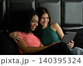 Happy young woman in green cloth that hug her smiling couple while lying on bed and using tablet pc together at home relaxing on weekend morning 140395324