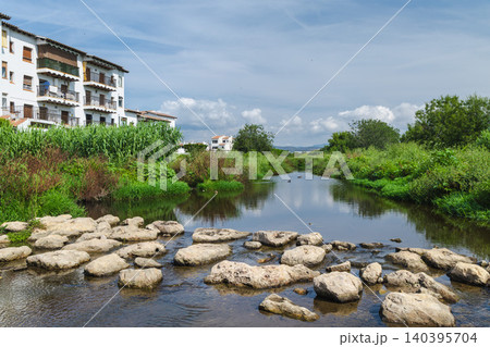 Rocky ford across a stream near the Les Madrigueres nature reserve in Sant Salvador, Catalonia, with residential buildings. 140395704