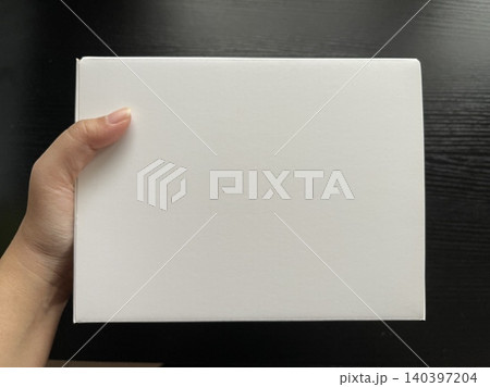 Hand Holding White Cardboard Box on Dark Wood Hand Holding White Cardboard Box on Dark Wood 140397204