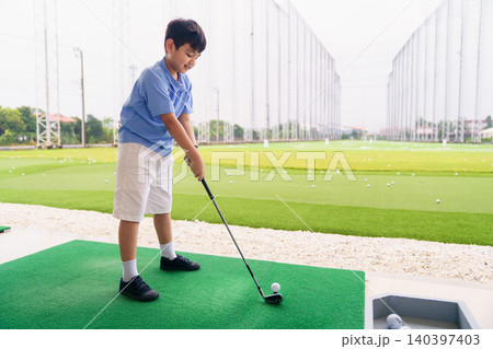 Golf instructor teaching young student proper swing at driving range 140397403