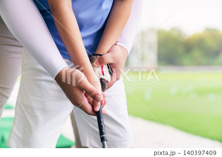 Close up of golf instructor teaching student how to grip club 140397409