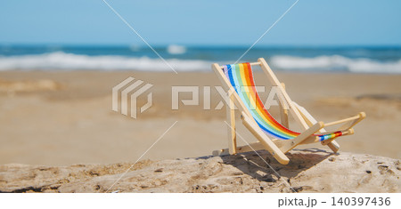 a rainbow striped deck chair on the beach, banner 140397436
