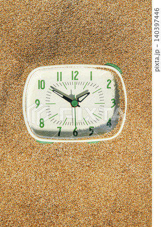 a mint green clock partially buried in sand a mint green clock partially buried in sand 140397446