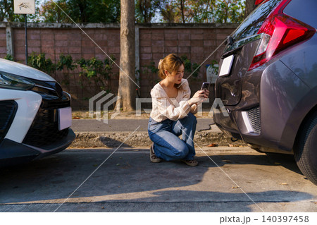 Woman inspecting damaged car bumper after minor accident 140397458