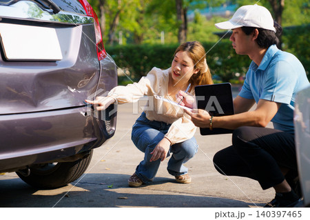 Insurance agent and woman inspecting car damage after accident Insurance agent and woman inspecting car damage after accident 140397465