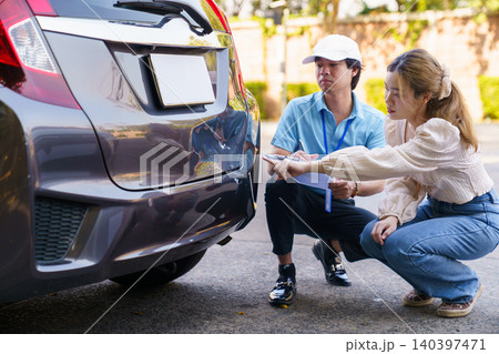 Insurance agent and woman inspecting car damage after accident Insurance agent and woman inspecting car damage after accident 140397471