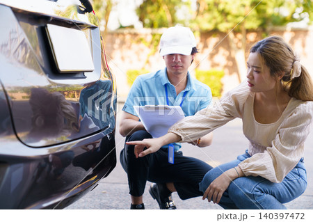 Insurance agent and woman inspecting car damage after accident 140397472