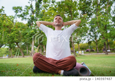 Peaceful man practicing yoga and meditation in green park 140397487