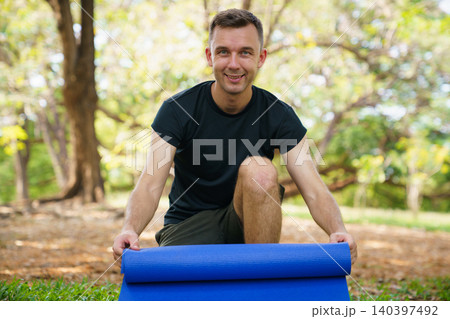 Fit man preparing exercise mat for outdoor yoga in the park Fit man preparing exercise mat for outdoor yoga in the park 140397492
