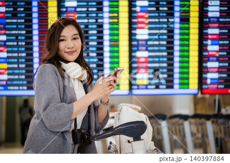 Happy woman checking flight status at airport information board Happy woman checking flight status at airport information board 140397884
