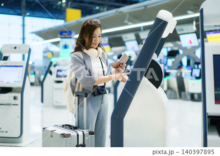 Asian woman using airport self service check in kiosk 140397895