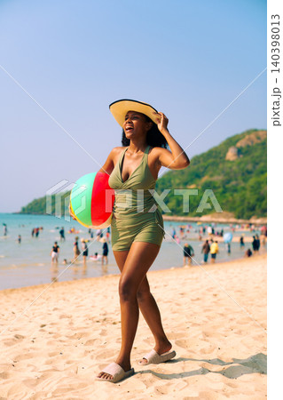 Happy Woman Holding Beach Ball on Sunny Tropical Vacation Happy Woman Holding Beach Ball on Sunny Tropical Vacation 140398013