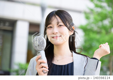 ハンディファンを持ってガッツポーズをする日本人女性 140398114