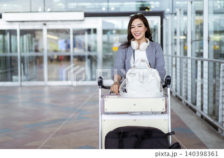 Happy Asian woman pushing luggage cart at airport terminal 140398361