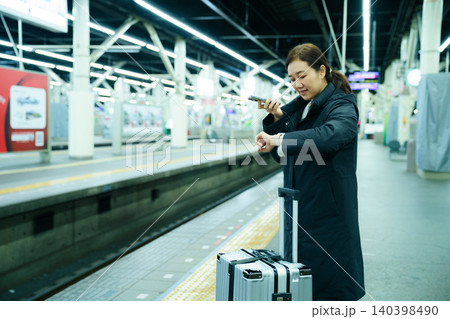 Asian woman using mobile phone while waiting at train station Asian woman using mobile phone while waiting at train station 140398490