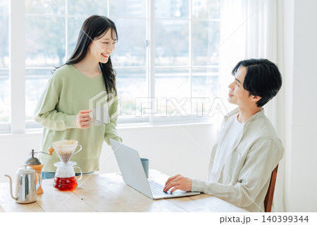 仕事中の男性にコーヒーを淹れる女性 仕事中の男性にコーヒーを淹れる女性 140399344