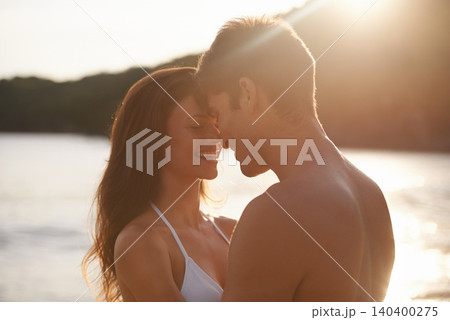 Love, sunset and couple on island for date on romantic anniversary vacation, adventure or holiday. Smile, bonding and young man and woman embracing with care by ocean on weekend trip together. Love, sunset and couple on island for date on romantic anniversary vacation, adventure or holiday. Smile, bonding and young man and woman embracing with care by ocean on weekend trip together. 140400275