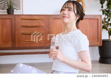 自宅でヨガの休憩中に水を飲む若い女性 自宅でヨガの休憩中に水を飲む若い女性 140400405