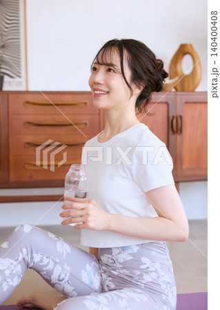 自宅でヨガの休憩中に水を飲む笑顔の若い女性 自宅でヨガの休憩中に水を飲む笑顔の若い女性 140400408