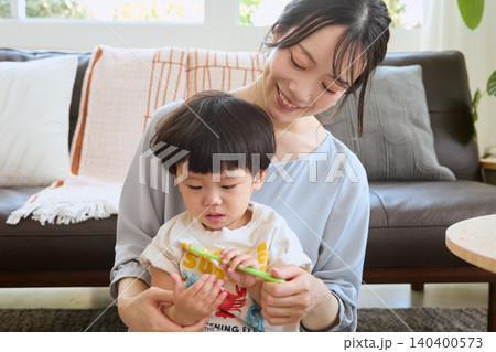 リビングで子どもに歯磨きを教える笑顔の若い母親 リビングで子どもに歯磨きを教える笑顔の若い母親 140400573