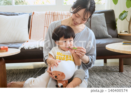 リビングで子どもの歯磨きをする笑顔の母親 リビングで子どもの歯磨きをする笑顔の母親 140400574