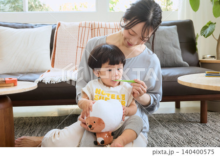 リビングで子どもの歯磨きをする若い母親 リビングで子どもの歯磨きをする若い母親 140400575