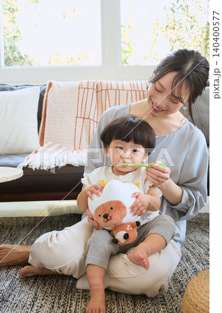 ソファで子どもの歯磨きをする笑顔の母親と幼児 ソファで子どもの歯磨きをする笑顔の母親と幼児 140400577