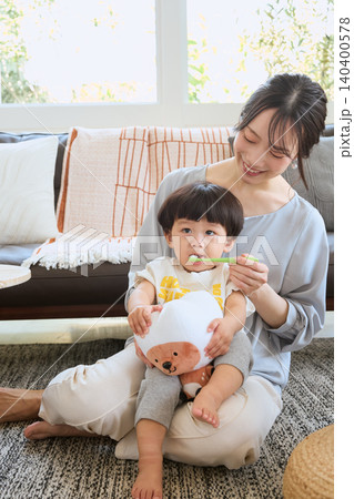 ソファで子どもの歯磨きをする笑顔の母親 ソファで子どもの歯磨きをする笑顔の母親 140400578