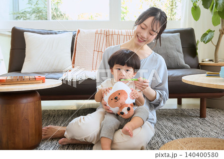 リビングで子どもの歯磨きをする笑顔の母親 140400580