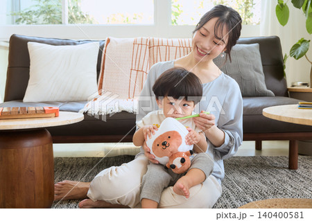 リビングで子どもを膝に乗せて歯磨きをする笑顔の母親 リビングで子どもを膝に乗せて歯磨きをする笑顔の母親 140400581