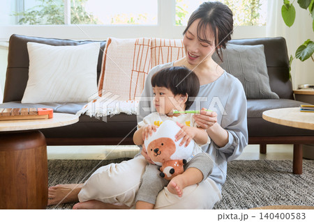 リビングで子どもの歯磨きをする笑顔の母親 リビングで子どもの歯磨きをする笑顔の母親 140400583
