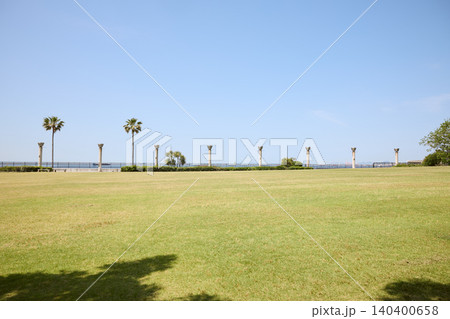 青空と広い芝生広場にヤシの木が並ぶ海沿いの 140400658