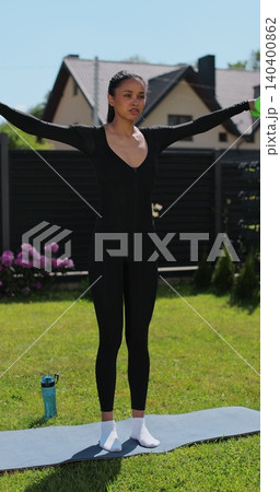 Vertical video. Young beautiful sports girl in leggings does exercises with dumbbells. Healthy lifestyle. Woman goes in for sports outdoor at home. 140400862