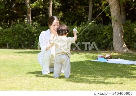 公園の芝生で幼い息子と遊ぶ笑顔の若い母親 公園の芝生で幼い息子と遊ぶ笑顔の若い母親 140400909