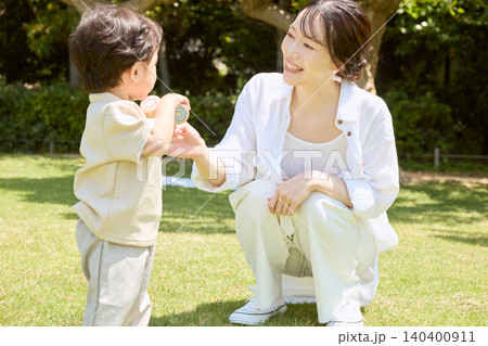 公園の芝生で小さな子どもと笑顔で遊ぶ若い母親 公園の芝生で小さな子どもと笑顔で遊ぶ若い母親 140400911