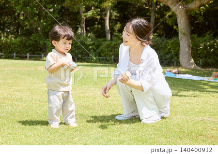 公園の芝生で小さな子どもと遊ぶ笑顔の若い母親 公園の芝生で小さな子どもと遊ぶ笑顔の若い母親 140400912
