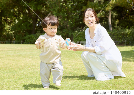 公園の芝生で積み木を持って遊ぶ幼児と笑顔の母親 140400916