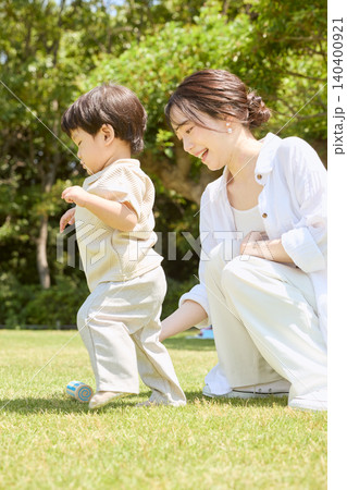 新緑の公園で子どもを抱き上げて遊ぶ笑顔の若い母親 140400921