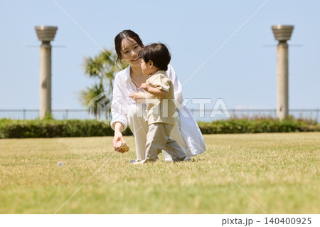 芝生の公園でシャボン玉を吹く母親と幼い息子 140400925