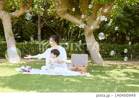 公園でシャボン玉を楽しむ母親と赤ちゃんのピクニック 公園でシャボン玉を楽しむ母親と赤ちゃんのピクニック 140400949