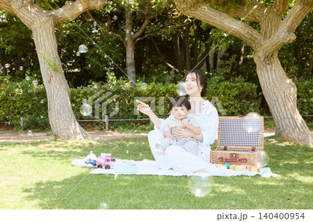 公園でシャボン玉を楽しむ母親と幼い息子のピクニック 公園でシャボン玉を楽しむ母親と幼い息子のピクニック 140400954