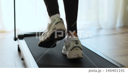 Closeup of a woman legs running on a treadmill at home. Back view of legs having workout on treadmill. 140401191