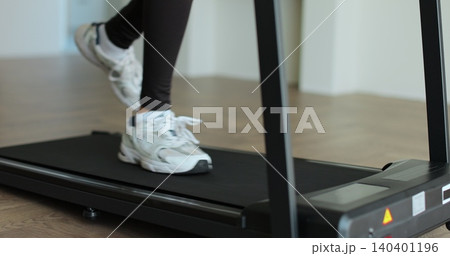 Sport sneakers feet moving fast on treadmill belt endurance exercise weight loss. Woman legs running on a treadmill at home. 140401196