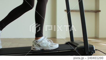 Sport sneakers feet moving fast on treadmill belt endurance exercise weight loss. Woman legs running on a treadmill at home. Sport sneakers feet moving fast on treadmill belt endurance exercise weight loss. Woman legs running on a treadmill at home. 140401200
