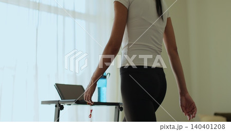 Woman having workout on treadmill back view. Fitness, girl and walking on treadmill in home for cardio exercise, wellness challenge and burning calories. 140401208
