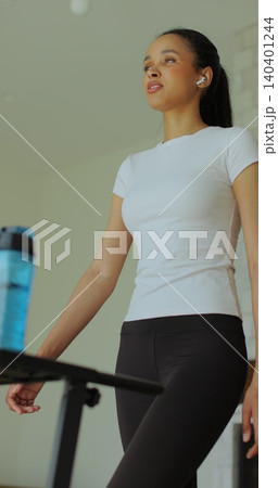 Vertical video. Workout, woman and walking on treadmill in home for cardio exercise, fitness challenge and burning calories. 140401244