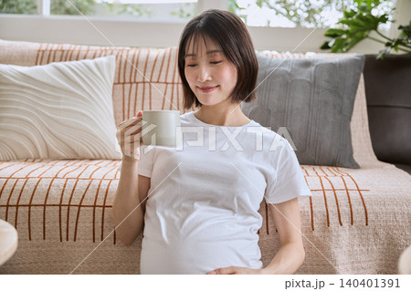 ソファでくつろぎながらマグカップを持つ妊婦の日本人女性 ソファでくつろぎながらマグカップを持つ妊婦の日本人女性 140401391