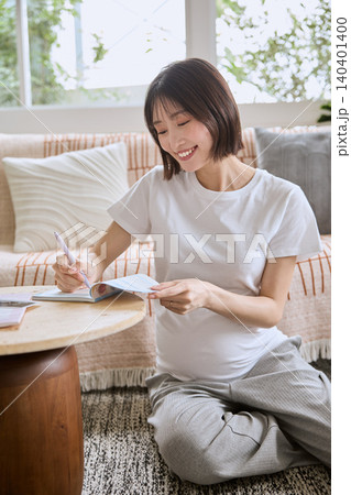 リビングのソファでくつろぎながら母子手帳を書く妊婦 リビングのソファでくつろぎながら母子手帳を書く妊婦 140401400
