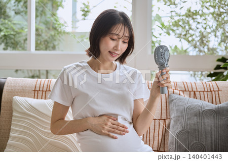 ハンディファンで暑さをしのぐ妊婦 ハンディファンで暑さをしのぐ妊婦 140401443